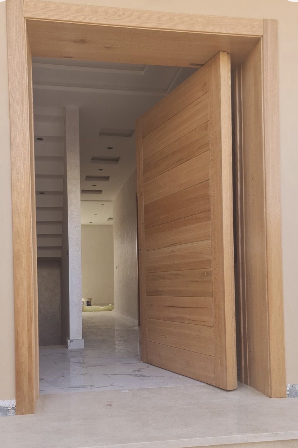 Porte pivotante en bois foncé deux battants poignée inox