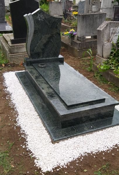 Pierre tombale granite vert avec stèle sculptée motif feuillage en cimetière
