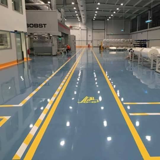 Sol époxy bleu brillant avec marquage au sol jaune et pictogrammes en usine