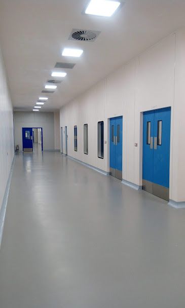 Sol époxy gris dans couloir d'hôpital avec portes bleues et éclairage