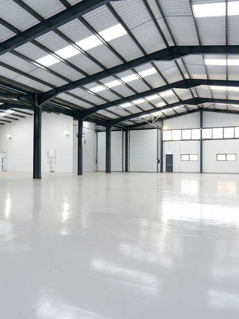 Sol époxy gris brillant dans hangar industriel avec charpente métallique