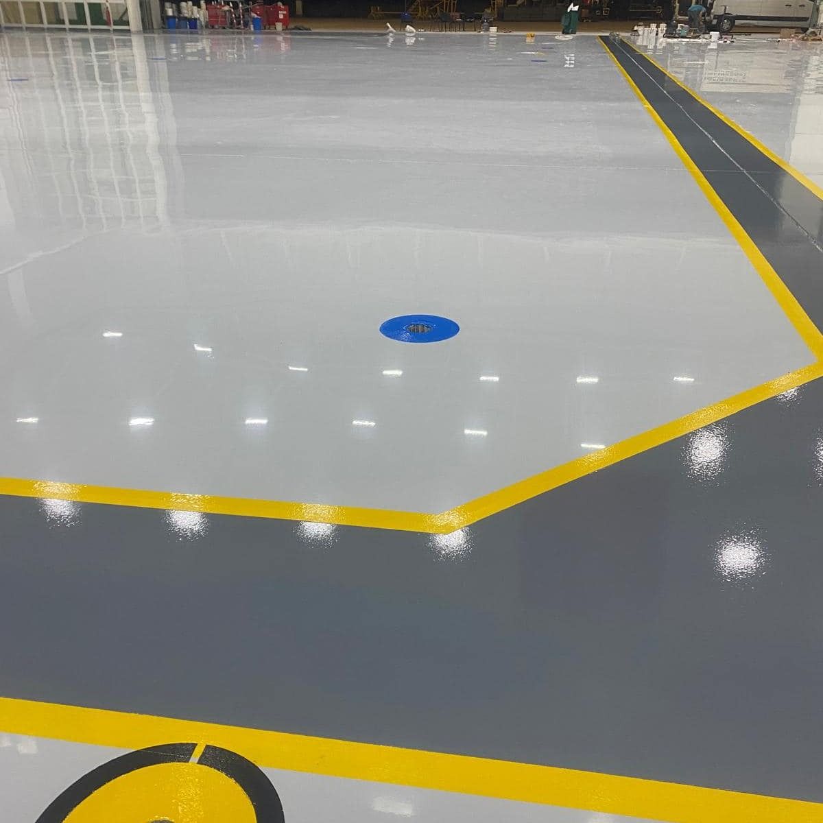 Sol époxy gris et anthracite avec zones délimitées jaunes en atelier industriel